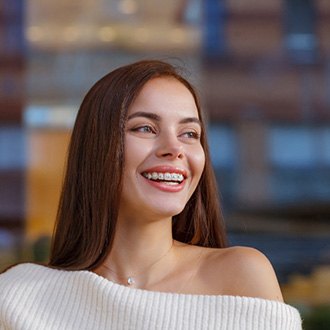 Woman in cream sweater smiling with braces