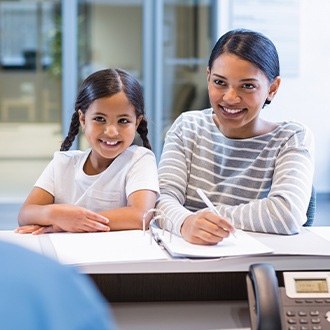 Dental patient and team member looking at dental insurance forms