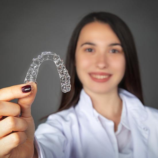 Smiling woman holding an Invisalign tray