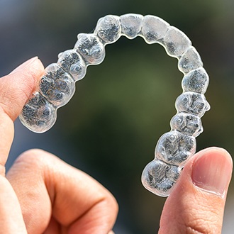 Hand holding up an Invisalign tray