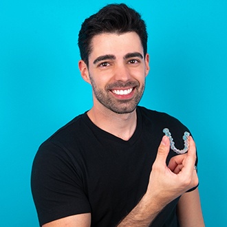 a young man holding his Invisalign aligner 