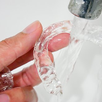 a patient rinsing off their Invisalign aligner
