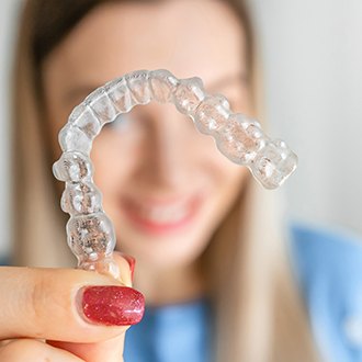 a patient holding her Invisalign aligner