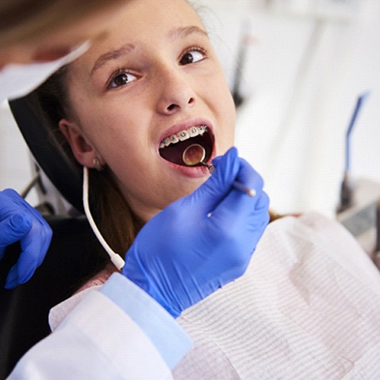 Orthodontist examining mouth of girl with braces