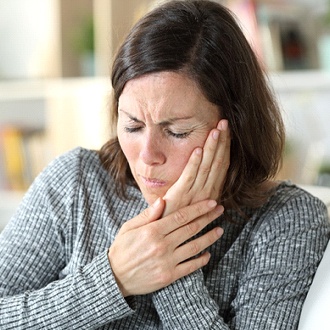 Woman experiencing tooth pain at home