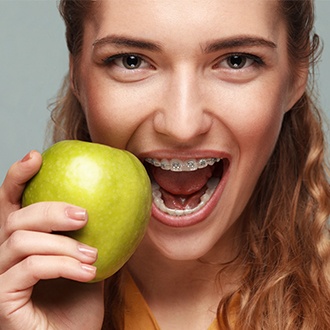 Woman with braces eating an apple