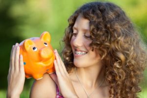 Woman with braces in Grafton holding piggy bank