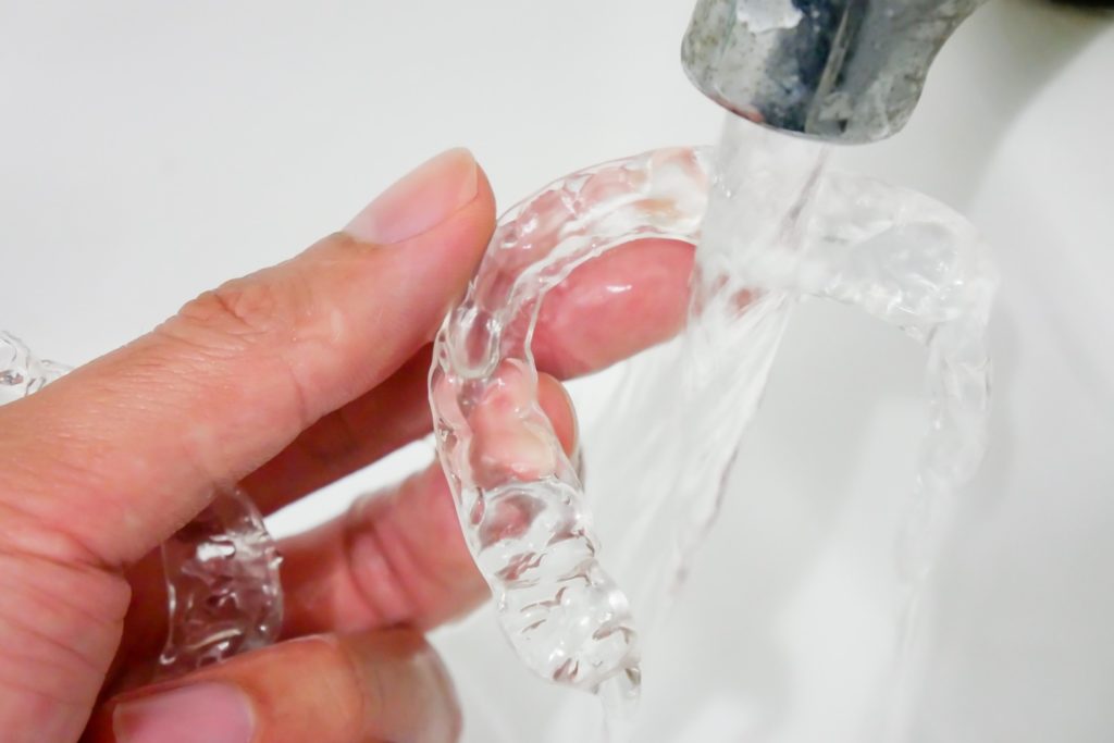 Patient rinsing Invisalign aligners in clean water