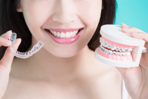 a person holding Invisalign and a model of braces