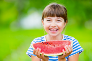 a child with braces eating a watermelon slice