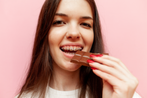 a girl with braces eating a chocolate bar